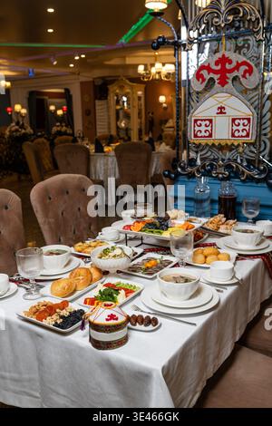 Beautifully set festive dining table richly laden with traditional Kazakh dishes: beshbarmak, soups, salads, fresh fruits, bread and desserts. Stock Photo