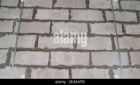 Close-up of metal profiles attached to a cinder block wall, providing support during a building construction or renovation project Stock Photo