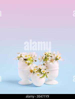 White Easter eggs with spring pear and strawberry flowers on a pink blue gradient background. Happy Easter concept. Greeting card. Stock Photo