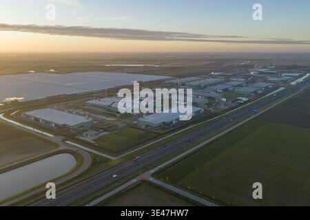 Aerial view of massive ai data center campus with multiple server halls and cooling infrastructure next to a highway, reflecting modern digital landsc Stock Photo