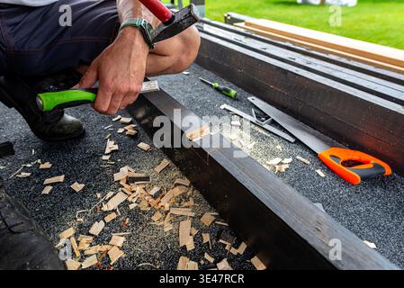 Carpenter using a chisel and hammer to create a mortise joint in a wooden beam Stock Photo