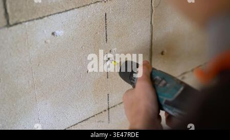 Worker using a cordless power drill to make a hole in a block wall. Stock Photo