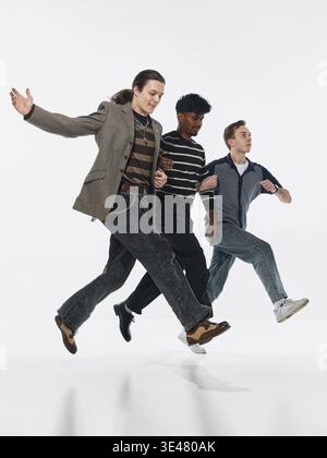 Three men walking in synchronized motion isolated on white background. Stock Photo