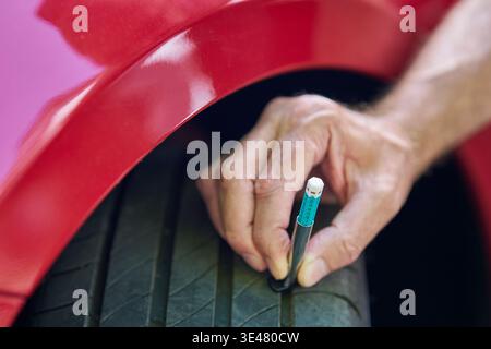 Close up of man using  gauge to check tyre tread depth on car Stock Photo