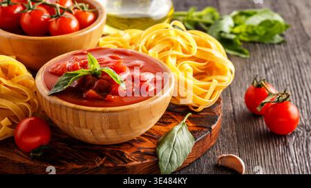Products for cooking - tomato sauce, pasta, tomatoes, garlic, olive oil on the old wooden background. Stock Photo