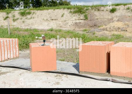 Filled Poroton bricks standing on the concrete foundation slab of a house under construction. Building materials prepared for masonry work on a reside Stock Photo