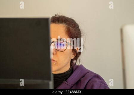 A woman looks at a computer screen with a concentrated expression while in smart work. The woman is thirty-nine years old Stock Photo
