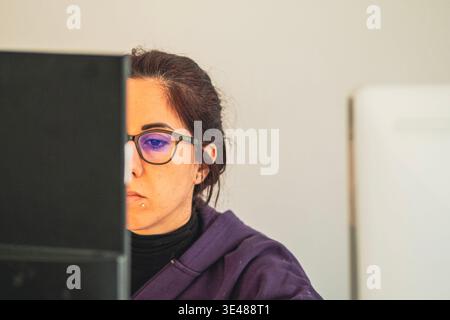 A woman looks at a computer screen with a concentrated expression while in smart work. The woman is thirty-nine years old Stock Photo