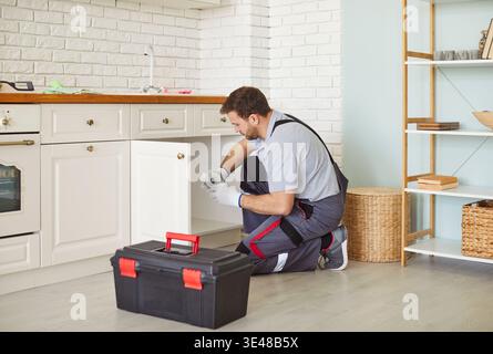 Focused Plumber Fixing Sink In Kitchen Stock Photo