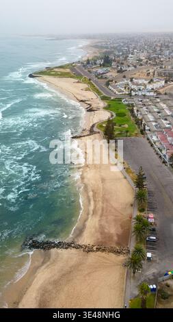 Aerial view of the coastline with sandy beaches, crashing waves, and urban development along the shore in Swakopmund, Erongo Region, Namibia. Stock Photo