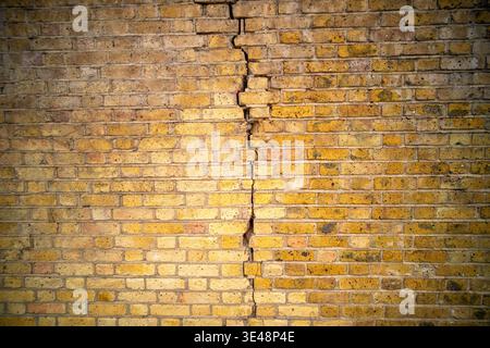 Weathered red British brick wall with dramatic crack texture background Stock Photo