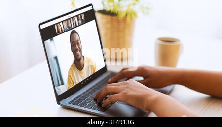 African American Woman Types on Laptop During Online Meeting With Coffee at Desk Stock Photo