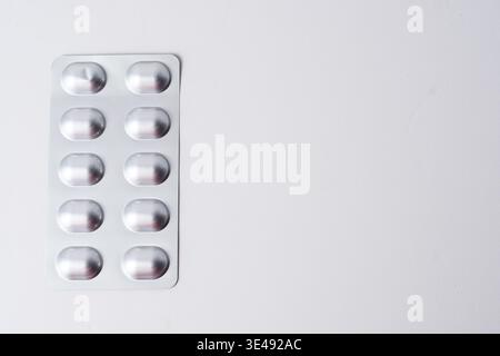 Empty silver blister pack isolated on white, minimalist pharmaceutical packaging background with strong copy space. Stock Photo