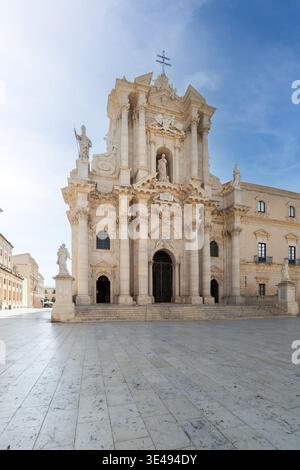 View of the ornate Baroque facade of the Cathedral of Syracuse in the stone-paved Piazza Duomo under a clear blue sky Syracuse, Sicily, Italy. Stock Photo