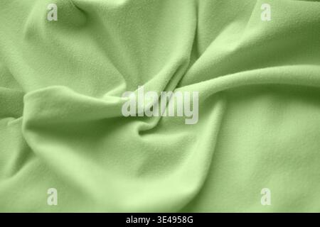 A top view of soft light green fabric with elegant wavy folds. Close up. Stock Photo