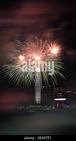 View of colorful fireworks exploding over the International Commerce Centre and the city skyline at night in Hong Kong. Stock Photo