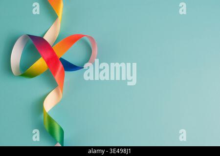 Rainbow Infinity Satin Ribbon on Blue Background Representing Autism Acceptance and Neurodiversity Concept Stock Photo
