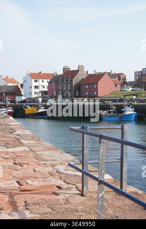 Harbour scene with moored boats and ladder on stone quay Stock Photo