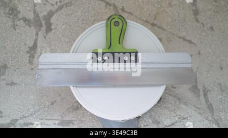 Construction worker using notched trowel and bucket for applying plaster during renovation Stock Photo