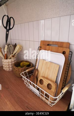 Organized Kitchen Utensils and Cutting Boards in a Modern Decorative Basket Setup Stock Photo