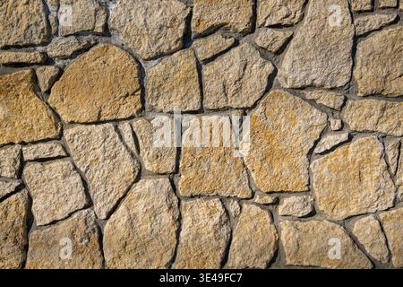 Natural Stone Wall Texture Background Closeup. Close-up of an irregular natural stone wall with visible mortar joints. Stock Photo