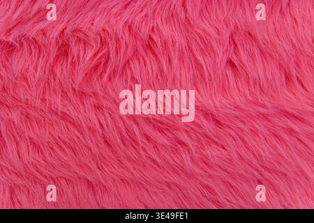 Bright Pink Faux Fur Texture Background. Close-up of soft bright pink faux fur with long fluffy fibers, creating a bold textured background for Stock Photo