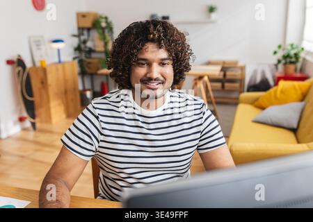 Young Indian man smiling while working at home office Stock Photo