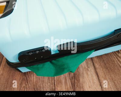 Blue suitcase features a combination lock and green fabric handle on wooden floor Stock Photo