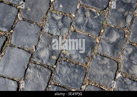 Dark grey ancient cobblestone pavement creating a textured background pattern Stock Photo