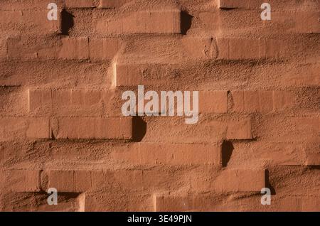 Rough red brick wall texture with strong shadows forming a geometric pattern Stock Photo