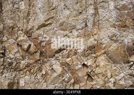 Rough natural rock surface showing brown and beige tones in a raw, geological background Stock Photo