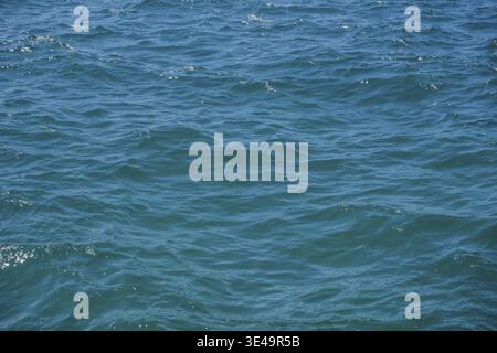 Blue and turquoise ocean water surface reflecting sunlight with small ripples and waves Stock Photo