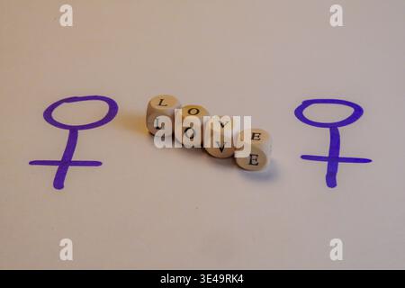 Two female gender symbols connected by wooden dice spelling LOVE on a white background Stock Photo