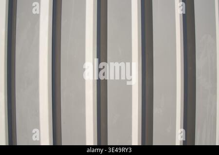 Corrugated metal surface featuring a pattern of alternating vertical gray and white stripes Stock Photo