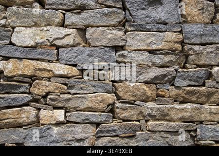 Stone wall showing irregular blocks creating a strong pattern and rustic background Stock Photo