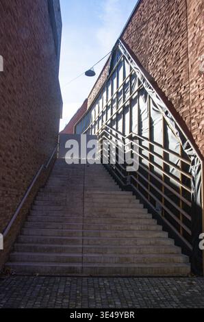 Concrete stairs ascending between modern red brick buildings under a blue sky Stock Photo