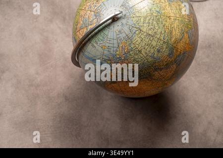 An old-fashioned globe on a grey texture with focus on the northern hemisphere, studio shot, top view, Germany Stock Photo