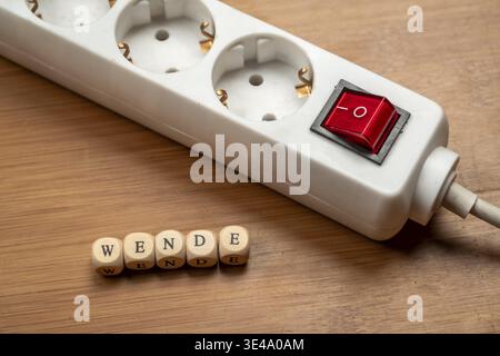 Concept image energy turnaround, switchable socket strip on wooden floor, letter cubes form the word turnaround, top view, studio image, Germany Stock Photo