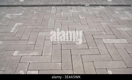 Grey paving stones in a herringbone pattern on an urban walkway. Stock Photo