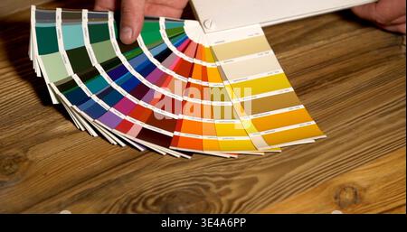 Collection of color samples displayed on wooden table during a design meeting in a studio setting with a person involved Stock Photo