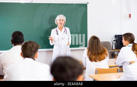 Female doctor explaining new theme to adult students during class in university Stock Photo