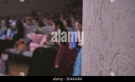 Graduation crowd blurring against textured wall, celebrating academic milestone with soft, unfocused energy and collective excitement Stock Photo
