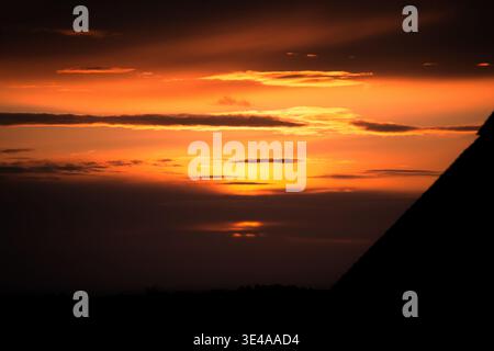 Golden Orange Burning Sunset Over Silhouetted Roofline With Dramatic Cloud Stock Photo