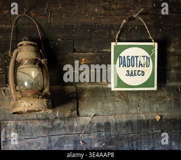Vintage lantern and work sign on a weathered wooden wall Stock Photo