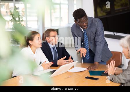 Angry middle-aged man shouting at his business partners sitting around table Stock Photo