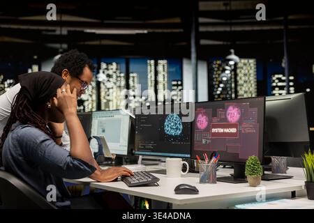 Young female programmer in office requests help from manager detecting and blocking hacker intrusion. Intern assisted by team leader coordinating incident response for network attack Stock Photo