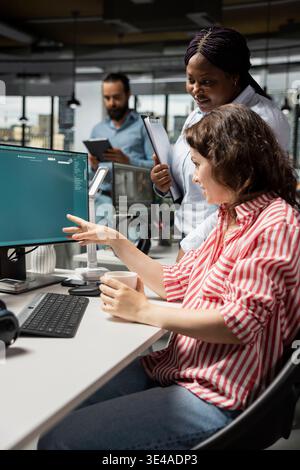Graphic editors generate images from prompts with text to image software, performing photo retouching. Diverse staff collaborating with artificial intelligence technology on monitor. Stock Photo