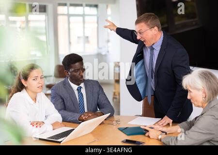Unbalanced evil mail head of department yells and blames employees for current problems. Stock Photo