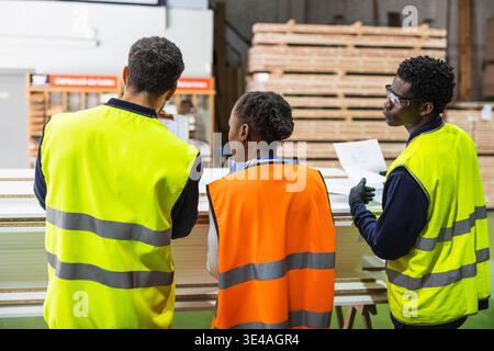 Workers reviewing inventory in a lumberyard warehouse Stock Photo