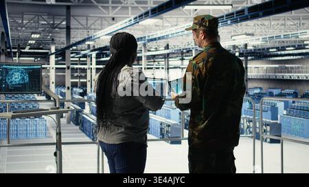 Military data center engineers using AI machine learning radar software to watch for enemy threats. Army technicians in data center use artificial intelligence on devices to detect dangers, camera A Stock Photo